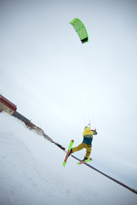 Low angle view of man skateboarding on snow against sky