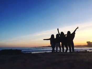 Silhouette people at beach against sky during sunset
