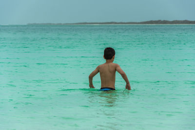 Rear view of shirtless boy in sea