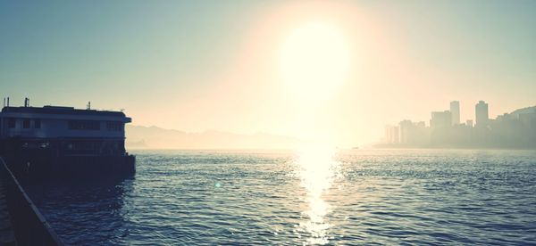 Scenic view of sea and buildings against sky at sunset