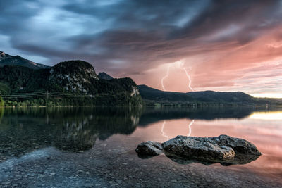 Scenic view of rock in lake against sky during sunset