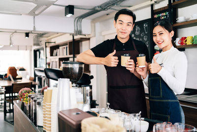 Couple holding coffee cup while standing in cafe