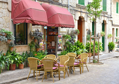 Chairs and tables at sidewalk cafe against buildings in city