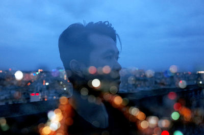 Portrait of man in city against sky at night