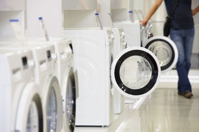 Low section of man standing by washing machine at laundromat