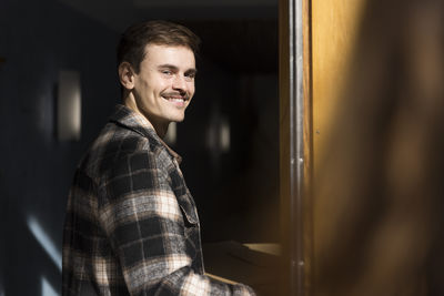 Side view portrait of smiling man entering in apartment building