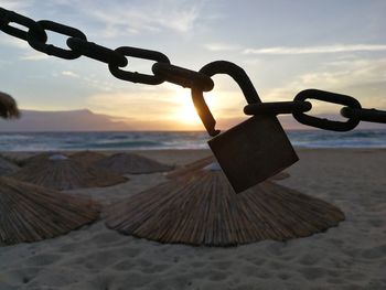 Close-up of chain on beach against sky during sunset