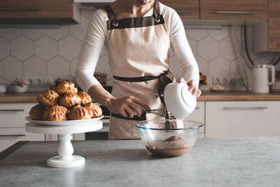 Midsection of female chef preparing cooking cup cake at kitchen