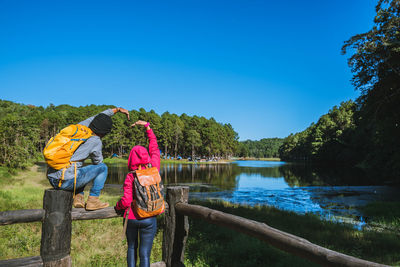 Rear view of woman by lake against clear sky