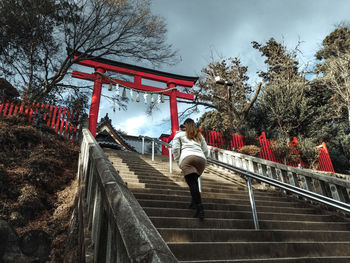 Rear view of woman on footbridge against sky