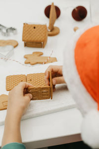 A child in a santa hat makes a gingerbread gingerbread house. new year's holidays. a christmas gift