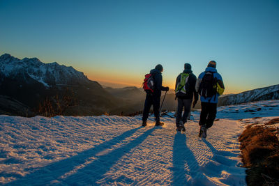 Rear view of people walking on snow covered mountain