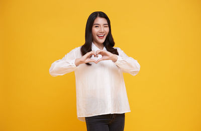 Portrait of a smiling young woman against yellow background