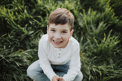 Portrait of smiling boy sitting against plants