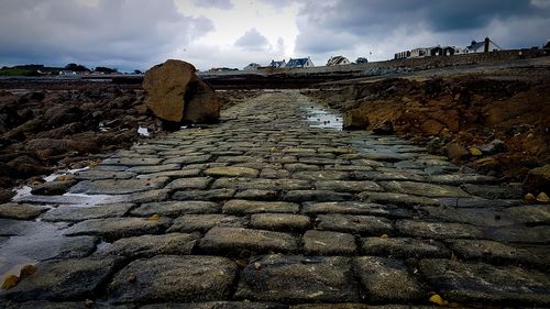 Cobblestone street amidst rocks against sky