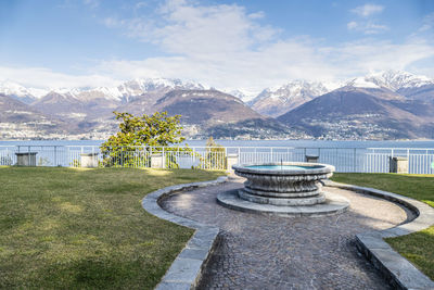 A fountain near the lake of como with the alps in background