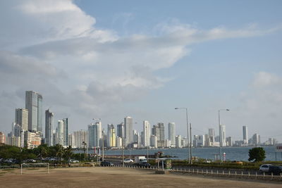City at waterfront against cloudy sky