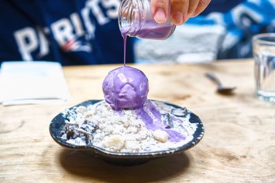Cropped image of hand pouring syrup on dessert