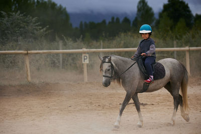 5-year-old girl riding on a horse, in a hipico club. infalltil sport concept.