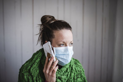 Portrait of young woman drinking against wall
