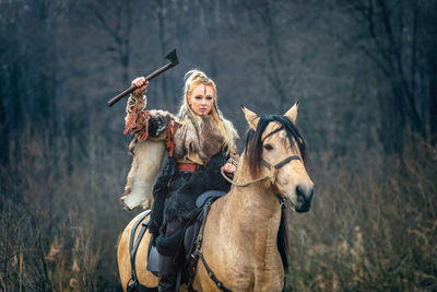 Portrait of woman with hand tool riding horse in forest