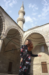 Low angle view of woman standing against building