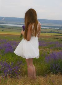 Rear view of woman standing on field against sky