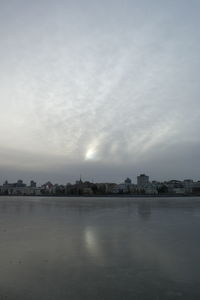Scenic view of river against sky in city