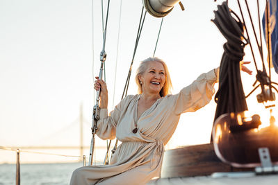 Senior woman standing at sailboat in sea