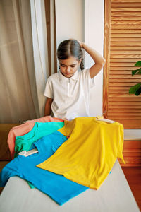 Girl chooses t-shirt among clothes at home. mockup friendly. t-shirts ready to have design