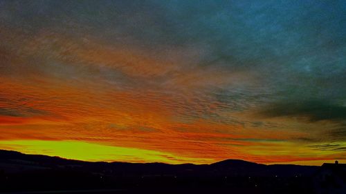 Scenic view of dramatic sky over silhouette landscape