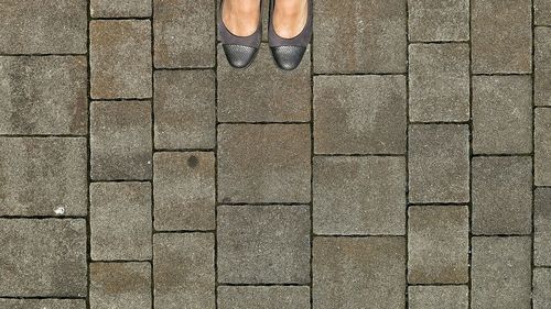 Low section of woman standing on footpath