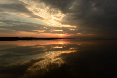 Majestic and beautiful sunset in the dark clouds of the sky above the calm water of the lake