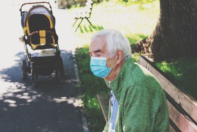 Portrait of old man wearing coronavirus mask standing on park