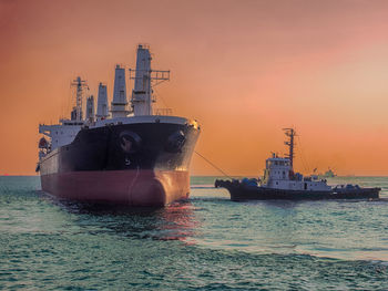 Boats in sea against sky during sunset