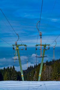 Electricity pylon by street against sky during winter