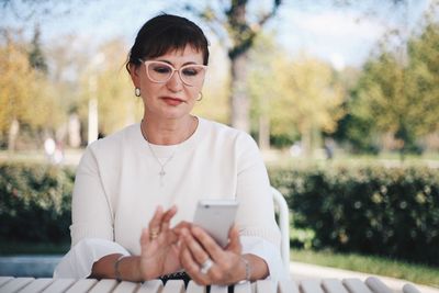 Mature woman using mobile phone while sitting outdoors