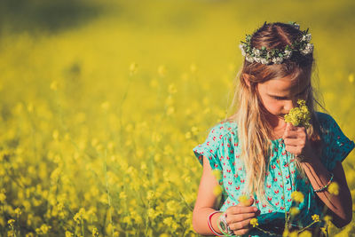 Girl smelling flowers on field