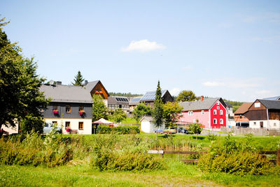 Houses and trees on field against sky