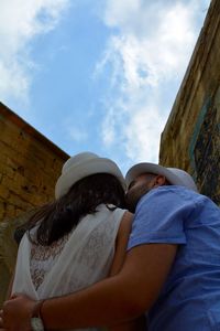 Low angle view of couple kissing against sky