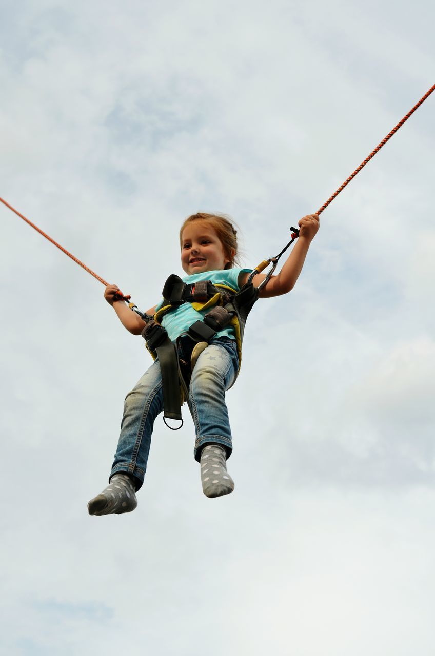 full length, childhood, fun, lifestyles, leisure activity, elementary age, enjoyment, low angle view, boys, person, sky, playing, casual clothing, girls, happiness, playful, mid-air, arms outstretched