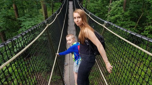 Portrait of mother with son standing on footbridge