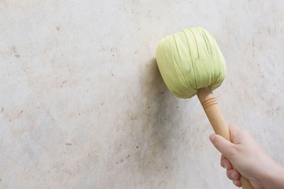 Cropped image of person holding bread against wall