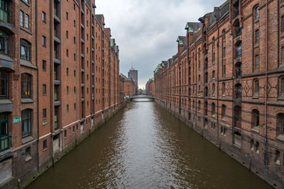 Canal amidst buildings in city against sky