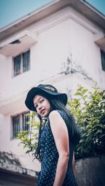 Portrait of woman standing against building