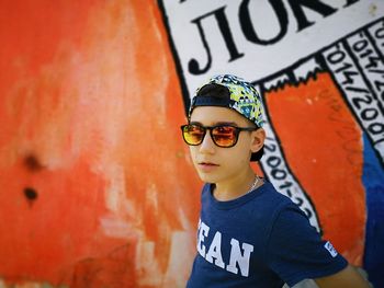 Portrait of boy wearing sunglasses standing against wall