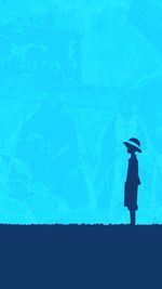 Rear view of silhouette woman standing against blue sky