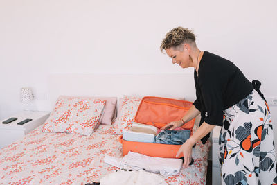 Side view of young man sitting on bed at home