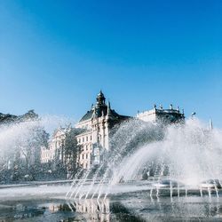 Water splashing in fountain against blue sky