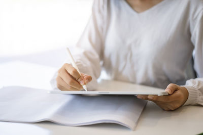 Midsection of man reading book on table